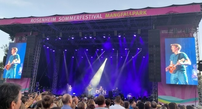 Foto: James Blunt mit Mini-Gitarre auf der Bühne und auf den großen Bildschirmen links und rechts der Bühne.