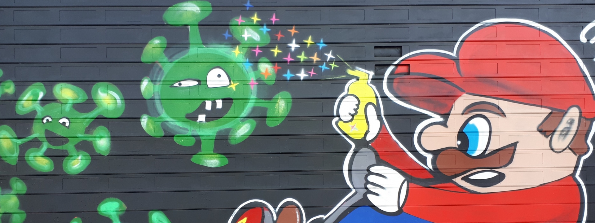 Foto: Graffiti auf einem Garagentor: Super Mario sprüht bunte Sternchen auf Corona Viren mit Gesichtern