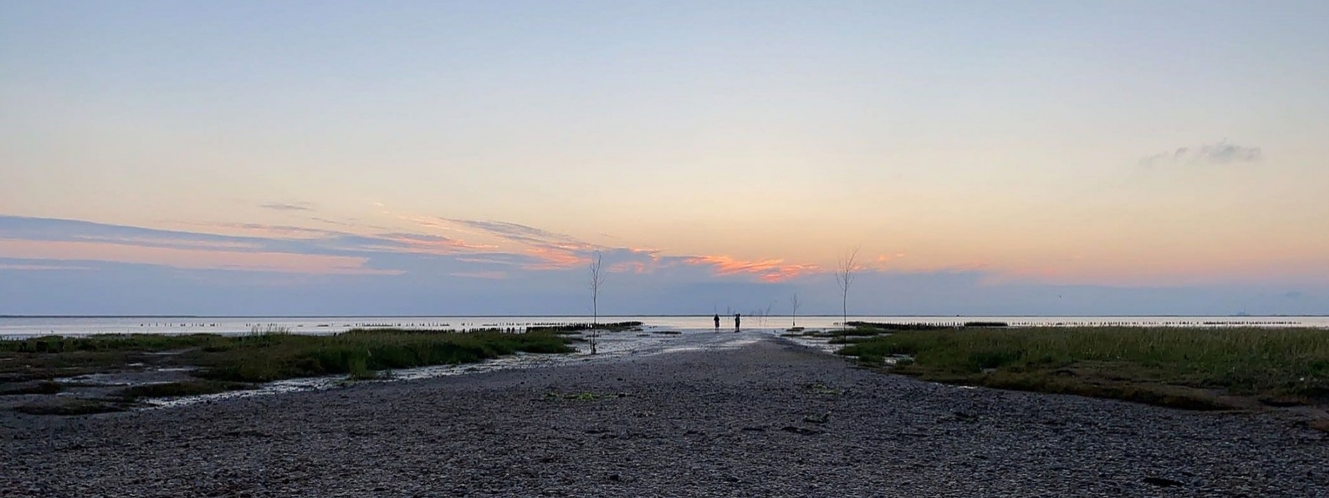 Foto: Zwei Personen winzig klein am Strand bei Sonnenuntergang