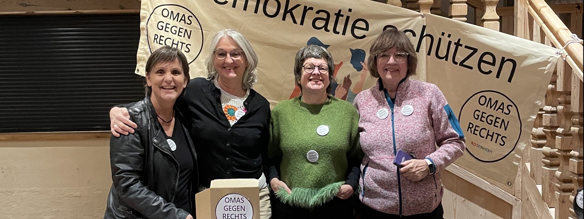 Aktive Omas beim Kaffkiez-Konzert | Foto: Omas gegen Rechts Rosenheim Vier ältere Frauen an einem Aktionsstand vor einem Banner mit der Aufschrift "Demokratie schützen" und mit "Omas gegen Rechts"-Buttons an ihren Pullis und Jacken