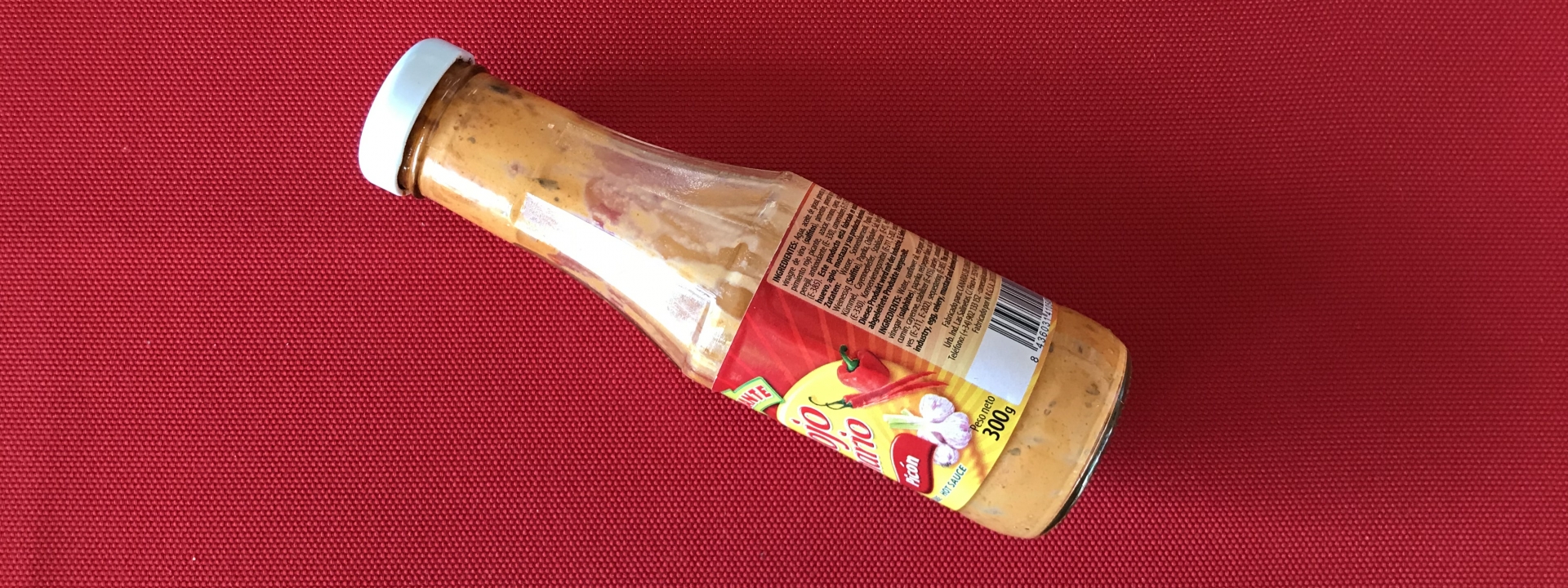 Foto: Eine halbleere Glasflasche mit  einer rosa Sauce darin, auf dem Etikett sind Paprika und Knoblauch zu erkennen