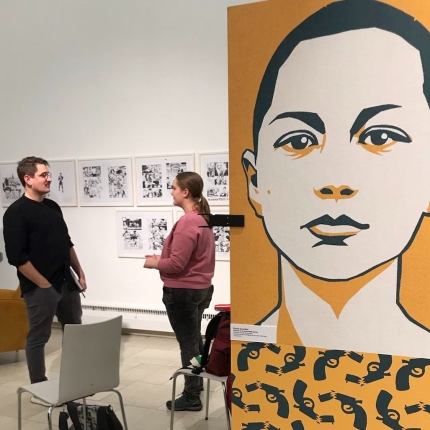 Foto: Im Vordergrund ein Portrait von Emma Gonzáles, im Hintergrund Benjamin Knödler im Gespräch mit aROund Redakteurin Franzi