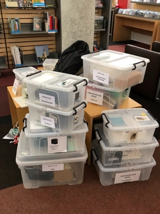 Foto: Einige gestapelte Plastik-Boxen mit Beschriftung, welche Dinge darin sind.