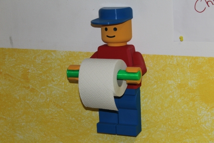 Foto zeigt einen Klopapier-Rollen-Halter in Form eines buntes Lego-Männchen aus Plastik.