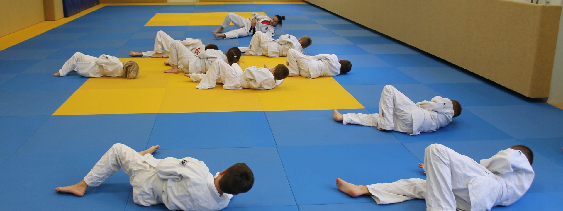 Judo-Training | Foto: KJR Ro Foto: Auf dem mit Matten ausgelegten Boden einer Turnhalle trainieren mehrere junge Leute in weißen Judo-Anzügen das richtige Fallen