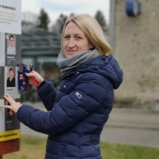 Foto: Eine Frau tackert ein Plakat an eine Wand