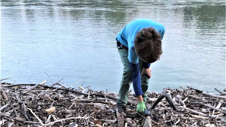 Foto: Ein Junge sammelt Müll an einem Flussufer auf
