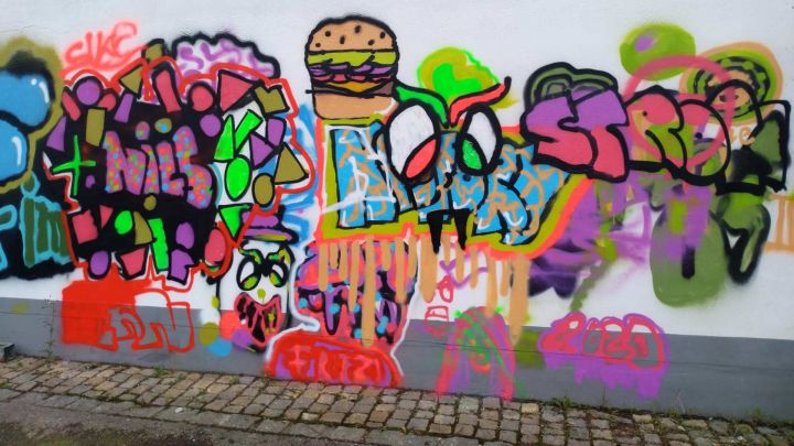 Foto, das ein buntes Durcheinander aus Graffitis mit Buchstaben und einem Hamburger zeigt