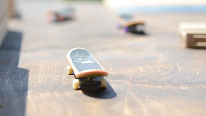 Foto: Nahaufnahme von einem Mini Skateboard auf einem Tisch, mit anderen Mini-Skateboards im Hintergrund.