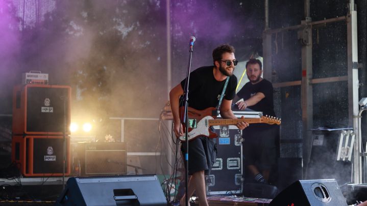 Foto: ein Musiker auf einer Bühne spielt Gitarre. Im Vordergrund sind Monitor-Boxen zu sehen. Im Hintergrund strahlt ein Scheinwerfer in den künstlichen Nebel.