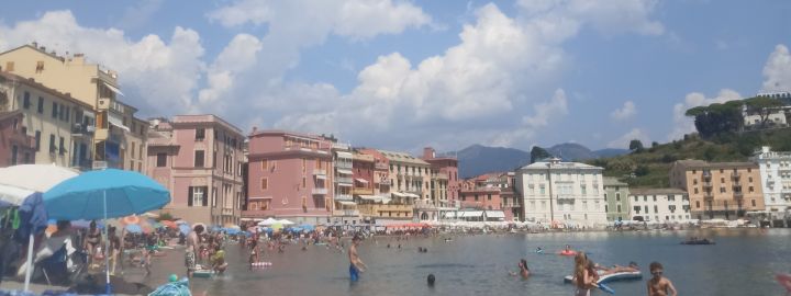 Foto: Ein schmaler gut besuchter Meeres-Strand mit farbenfrohen Häusern ganz nah am Wasser