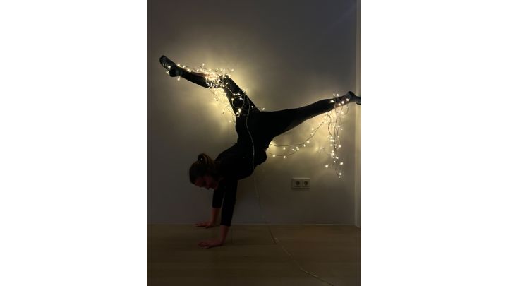 Foto: Hannah im akrobatischen Handstand mit der Lichterkette an ihren Füßen in der Luft.
