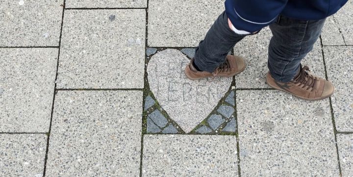 Foto: Auf einem gepflasterten Gehweg ist ein steinernes Herz eingelassen mit der Aufschrift "Leben leben"