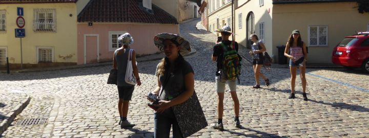 Foto: 5 Jugendliche in sommerlicher Kleidung und mit Fotoapparaten an einem kleinen Platz mit Kopfsteinplflaster 