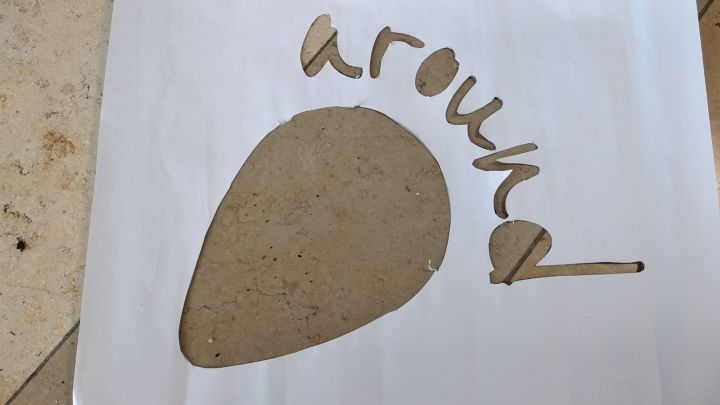 Foto: Eine Schablone des aROund Logos ausgeschnitten aus einem weißen Papier liegt auf einem Steinboden